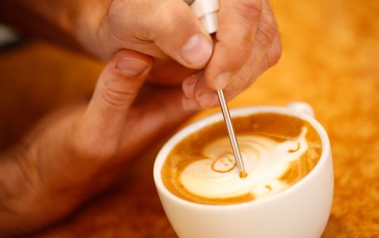 A Close Up Of A Person Holding A Cup Of Coffee